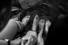 Three people's feet together in a shallow pool